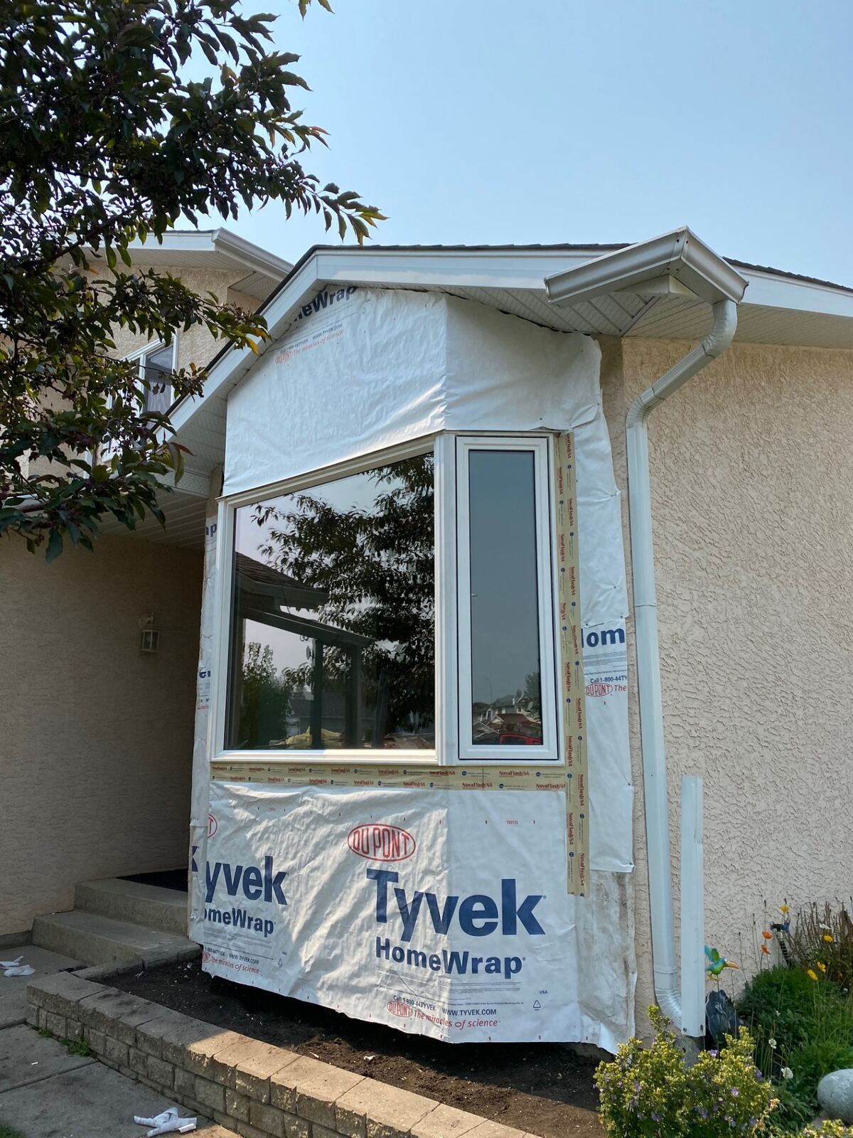 Bay window installed mid-renovation with house wrap and trim ready for siding