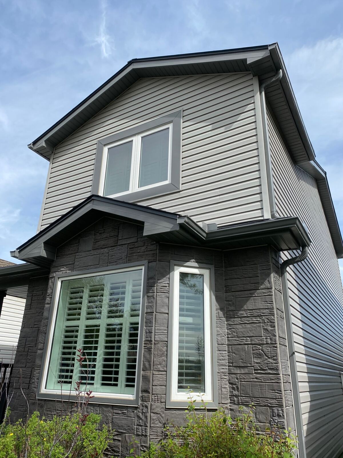 Grey two-storey home with stone wainscot and large windows